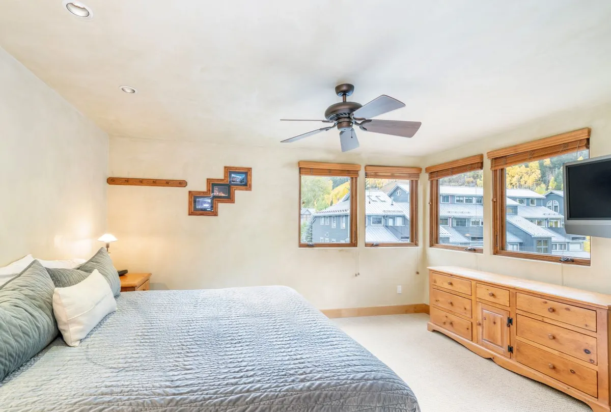 A tranquil king bedroom with a comfortable bed, wide windows for natural light, a dresser, and decorative accents, creating a serene and restful atmosphere.